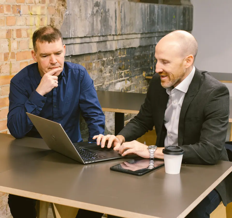 Lee Smith and Ian Welch, the founders of Network London, sitting at a table looking at a laptop